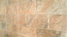 Detailed texture of a natural stone wall with earthy tones and rough surface.